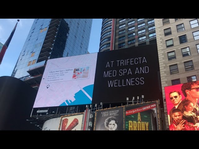 A giant outdoor billboard featuring a beauty campaign with a crowd gathered beneath